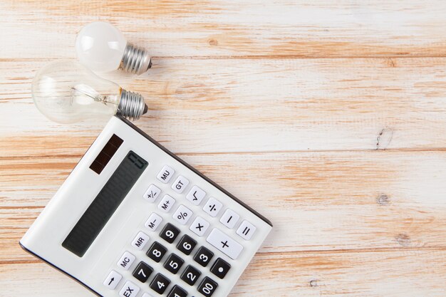 Calculator and light bulbs on wooden scene