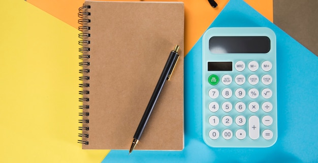 Calculator and notebook on multi-colored pieces of paper. desktop concept