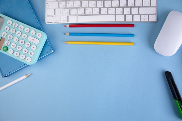 Calculator on notebook with pencils and keyboard on the table