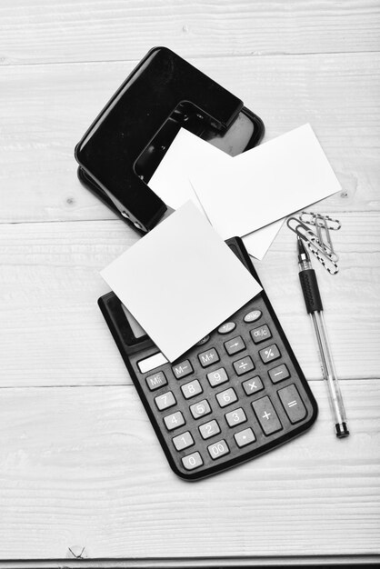 Photo calculator notes paper clips hole punch pen on wooden surface