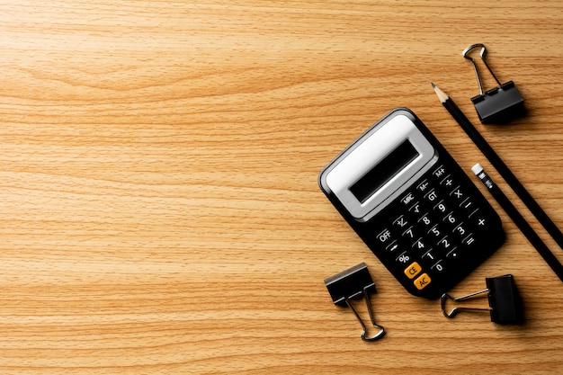 Calculator and office supplies on wooden table. 