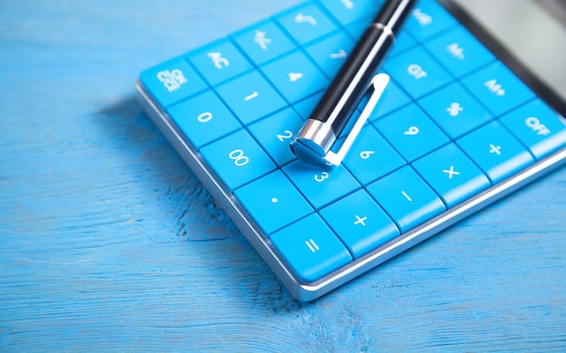 Premium Photo | Calculator and pen on the blue background
