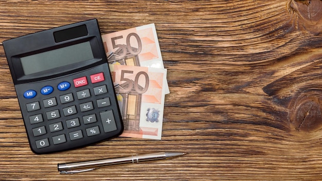 Calculator pen and euro on wooden table