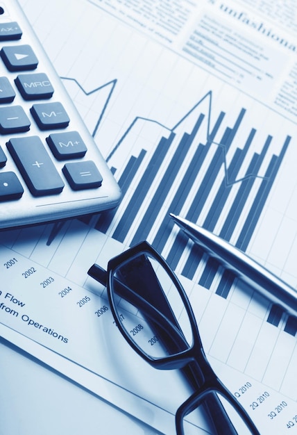 Calculator, Pen and Eyeglasses on Business Graphs