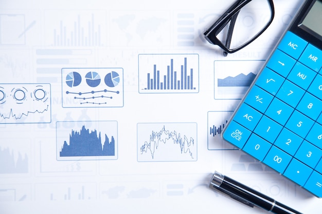 Photo calculator, pen, eyeglasses on financial graphs