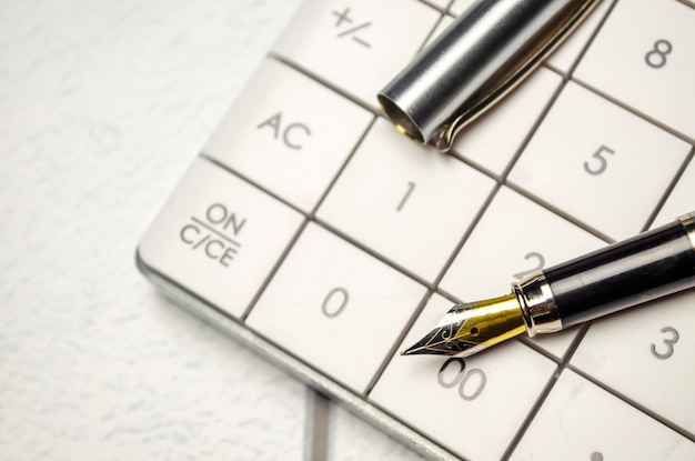 Calculator pen and eyeglasses on wooden table