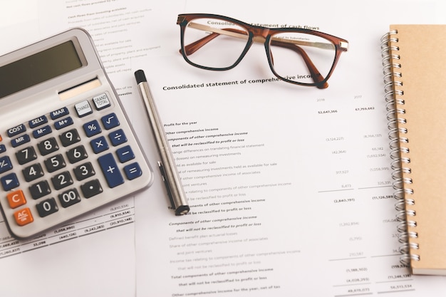 Калькулятор, ручка и очки на документах финансового анализа