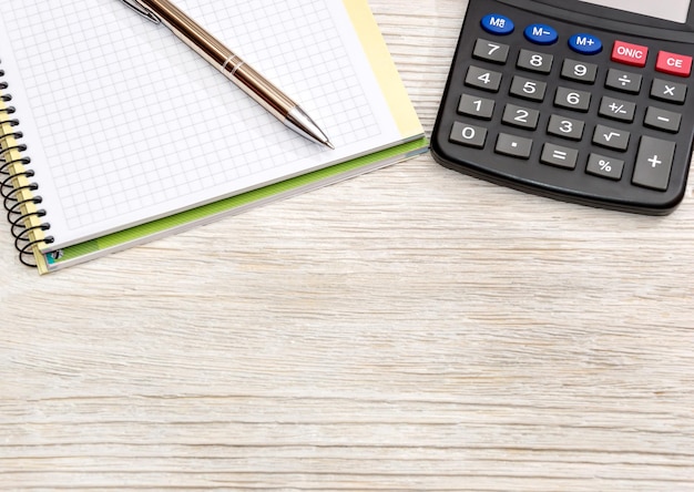 Calculator pen and notepad on wooden table