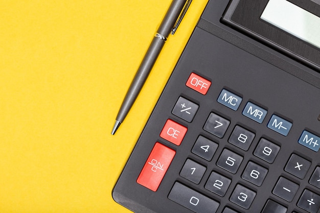 Calculator and pen on yellow background economy or business concept background