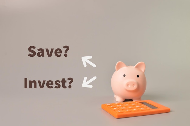 Calculator and piggy bank with questions SAVE or INVEST
