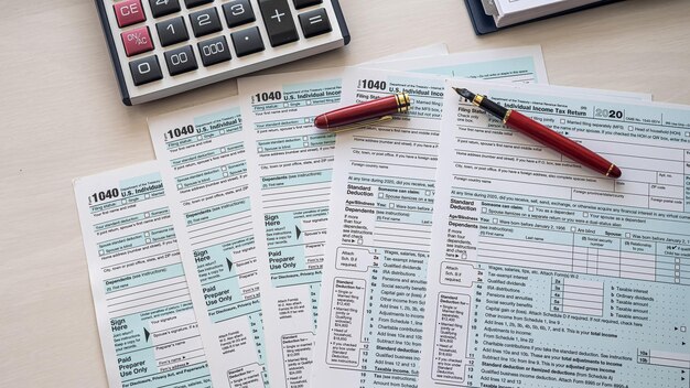 Calculator red pen tax forms 1040 spread out on a spacious table Documentation concept