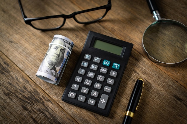 A calculator and a roll of dollar banknote.