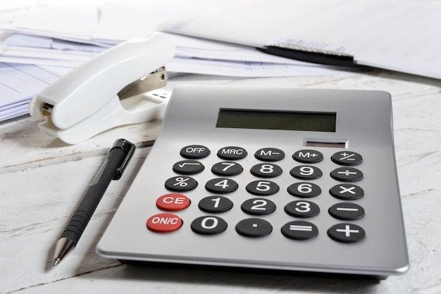 Calculator and stapler on a white wooden table