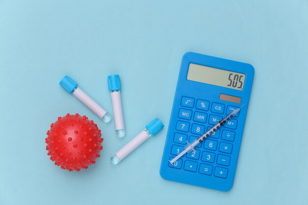 Calculator, virus strain model, medical test tubes with syringe on blue background. Vaccination. Top view