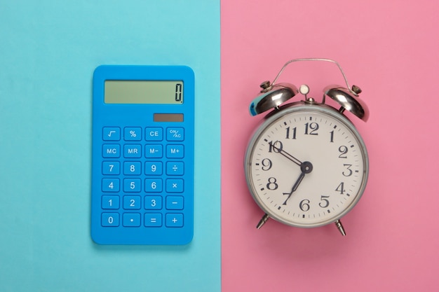 Calculator with alarm clock on pink blue pastel. Back to school. Education concept