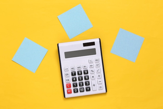 Calculator with blank memo papers on yellow background