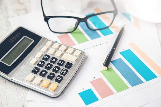 Calculator with glasses on graph on desk