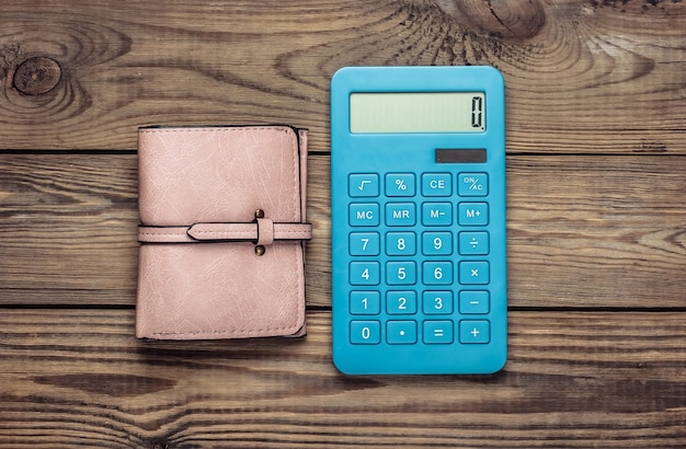 Calculator with leather wallet on wooden table