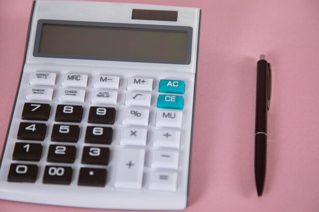 Calculator with pen on pink background