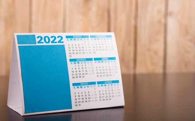 calendar 2022 months in spanish on desk table and wooden planks background