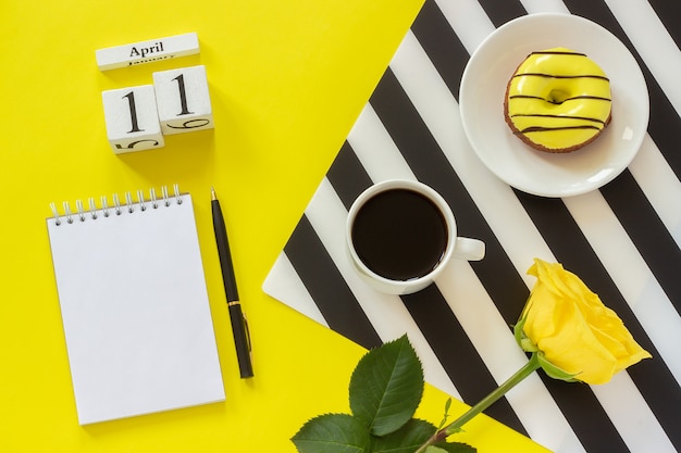 calendar April 11th. Cup of coffee, donut, rose, notepad. Concept stylish workplace