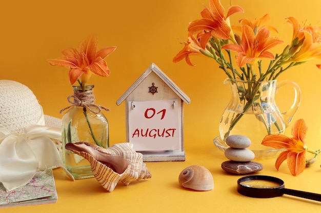 Calendar for August 1 decorative house with numbers 01 name of the month august in English bouquets of daylilies sea shells and stones summer hat on an orange background side view