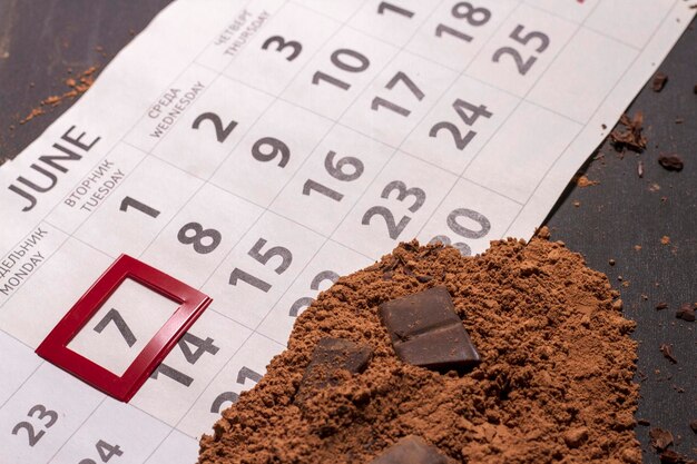 Calendar closeup with broken chocolate bar and cocoa powder World chocolate day 7 july