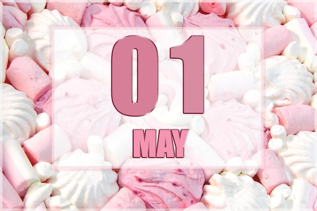 흰색과 분홍색 마시멜로를 배경으로 한 달력 날짜 5월 1일은 그 달의 첫째 날입니다.