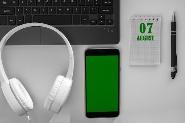 デスクトップと緑色の画面の携帯電話の明るい背景にあるカレンダーの日付 8 月 7 日は月の 7 日目です