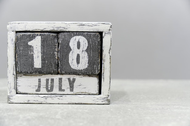 Calendar for July 18 made of wooden cubes on gray backgroundWith an empty space for your text