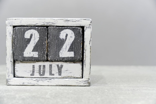 Календарь на 22 июля из деревянных кубиков на сером фонеС пустым местом для текстаМозг и День подарков