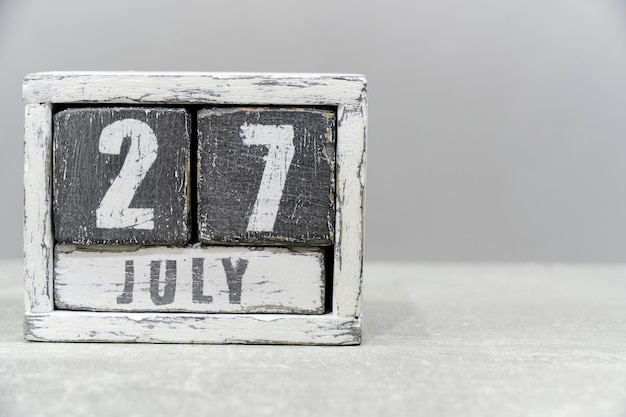 Photo calendar for july 27 made of wooden cubes on gray backgroundwith an empty space for your textworld fishing day