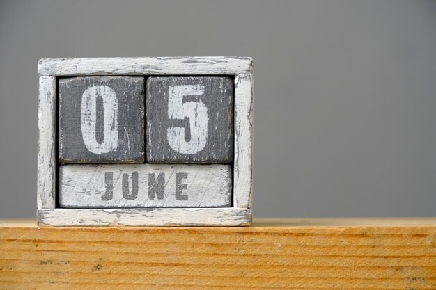 Calendar for June 05 made of wooden cubes standing on shelf on gray backgroundWith an empty space for your text