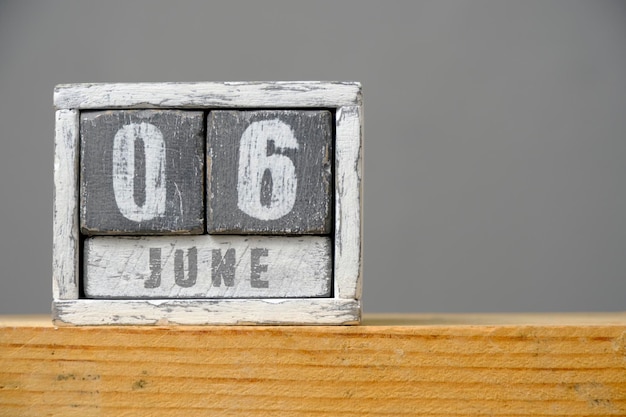Calendar for June 06 made of wooden cubes standing on shelf on gray backgroundWith an empty space for your text