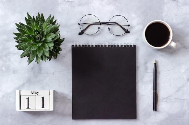  calendar May 11. Black notepad, cup of coffee, succulent, glasses on marble 