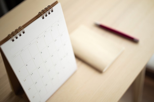 Calendar page close up on wood table background with pen and\
notebook business planning appointment meeting concept