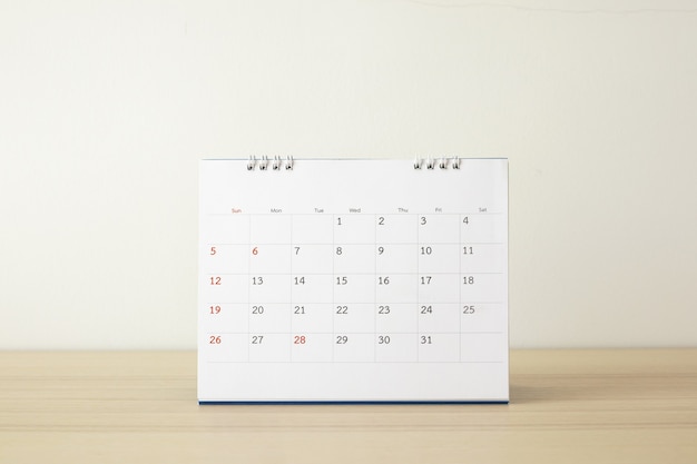 Calendar page close up on wood table with white wall background business planning appointment meeting concept