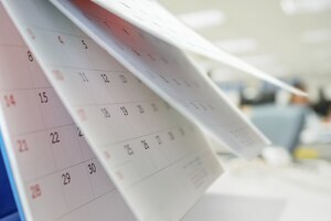 calendar page flipping sheet on table with blurred office interior background business schedule planning appointment meeting concept