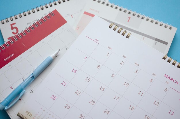 calendar page with pen close up on blue background business planning appointment meeting concept