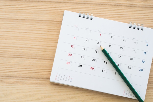 Calendar page with pencil on wood table