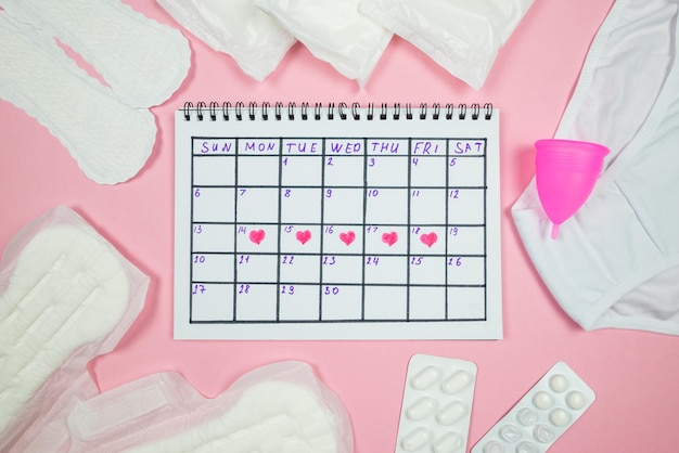 Calendar photo underwear menstrual cup sanitary napkins on isolated pastel pink background The concept of menstruation women's creative days