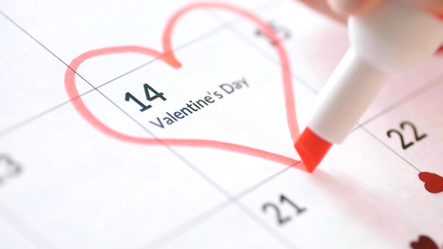 Лист календаря с датой 14 февраля, отмеченной красным сердечком с помощью маркера "День святого Валентина"