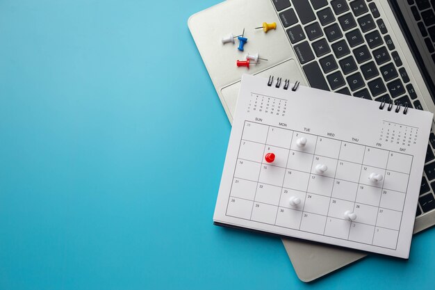 Calendar on solid ã&â¸â´blue background with copy space,\
pinned in a calender on datebusiness meeting schedule, travel\
planning or project milestone and reminder concept.