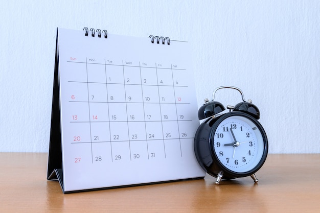 Calendario con giorni e orologio sul tavolo di legno