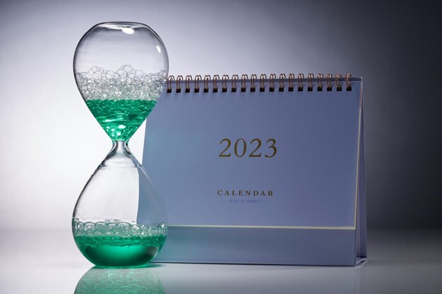 Calendar with liquid type of hour glass against gray background