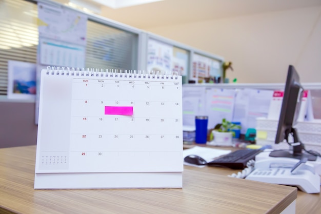 Photo calendar with paper note on office desk for events planner.