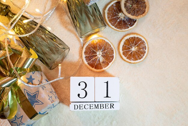 Фото Календарь с датой 31 декабря на фоне апельсинов очки гирлянды на бежевом фоне декор рождество