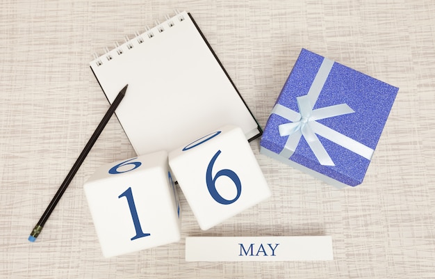 Фото Календарь с модным синим текстом и цифрами на 16 мая и подарком в коробке.