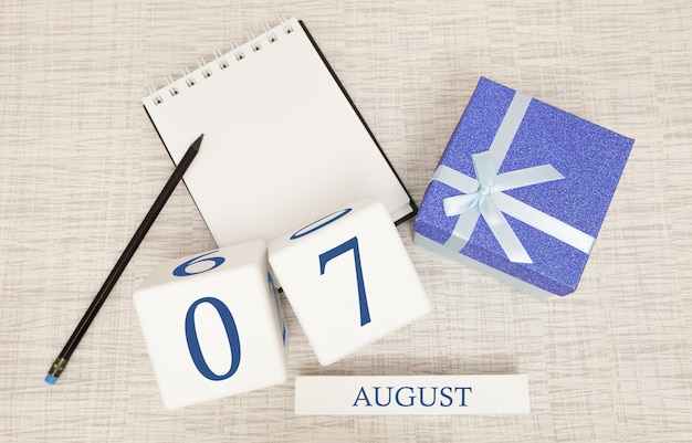 Foto calendario con testo blu e numeri alla moda per il 7 agosto e un regalo in una scatola.