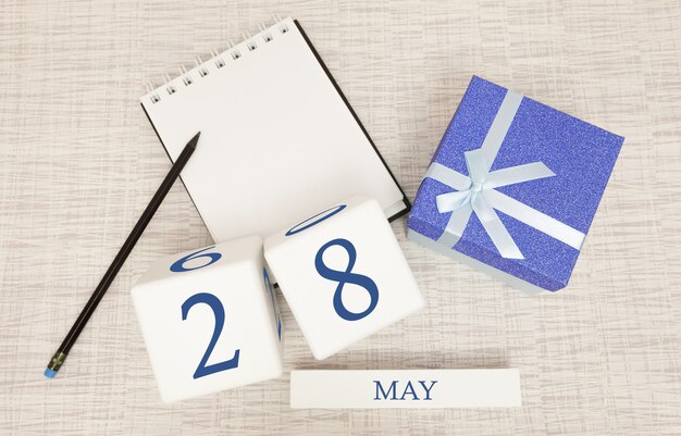 Calendario con testo blu e numeri alla moda per il 28 maggio e un regalo in una scatola.